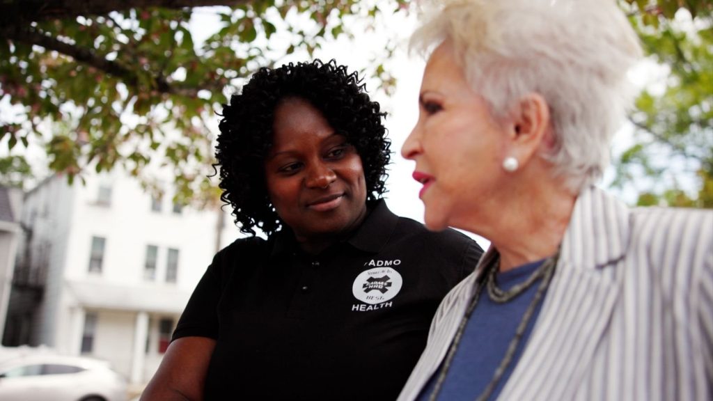 FADMO Health caregiver from our Bronx home care agency walking with a senior woman on a residential street