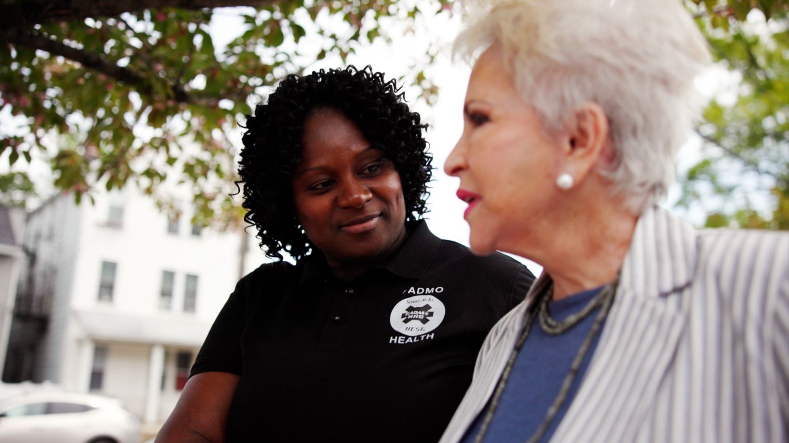 FADMO Health caregiver from our Bronx home care agency walking with a senior woman on a residential street